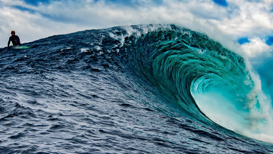 a large wave with a surfer sitting on his board