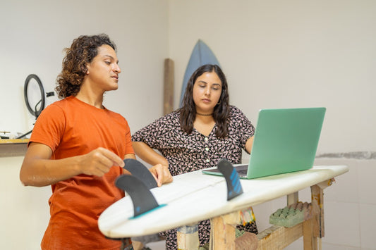Young and latin colleagues using digital tablet in a surfboard repair shop